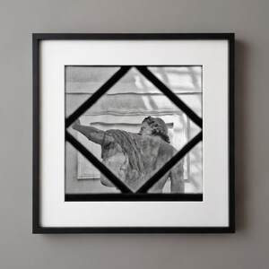 Può includere: Stampa in bianco e nero incorniciata di una statua classica, vista attraverso una cornice a forma di diamante. La statua è drappeggiata con tessuto e l'immagine è incorniciata su una parete grigia neutra.