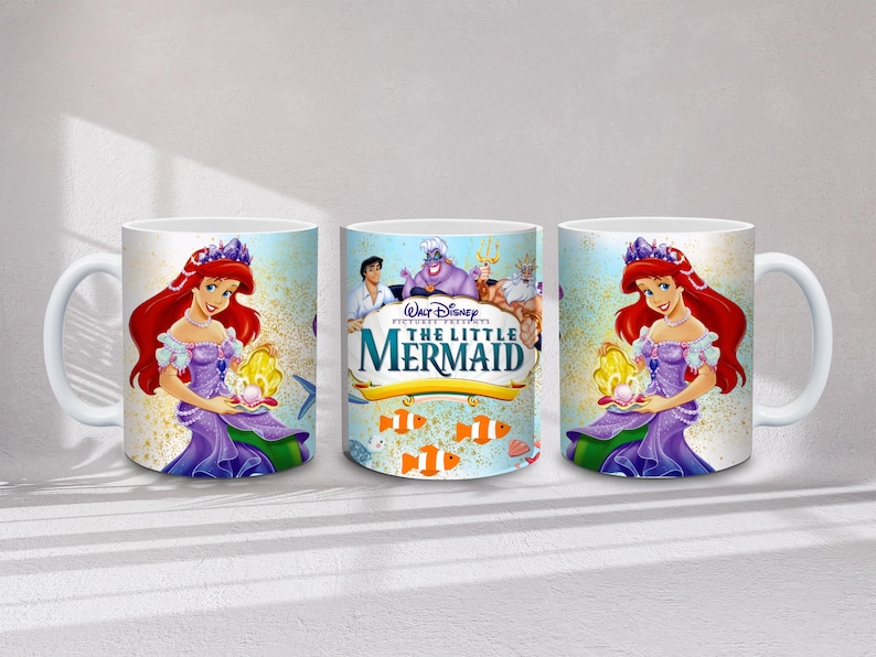 May include: White ceramic mug featuring Ariel from Disney's The Little Mermaid. The design includes Ariel with red hair and a purple dress, holding a shell. The center mug displays the movie title and characters.