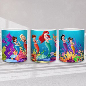 May include: Three white ceramic mugs with wraparound mermaid designs. Each mug features a different mermaid with red, blonde, and brown hair, set against a vibrant underwater scene with colorful coral and fish.