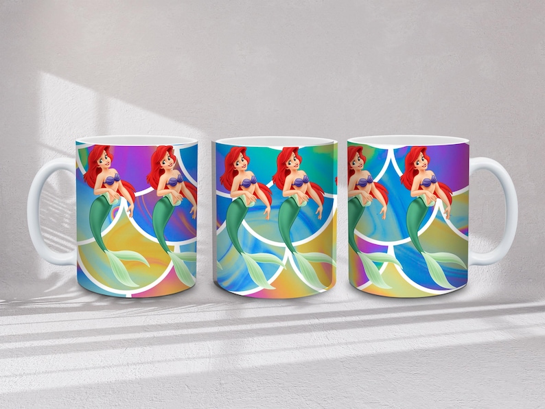 May include: Three white ceramic mugs featuring a mermaid with red hair, a purple seashell bra, and a green tail. The mermaid is set against a colorful, abstract background. Each mug has a white handle.