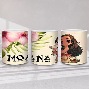 May include: White ceramic mug with the word "MOANA" in black, alongside pink hibiscus flowers and green leaves. The mug also features a cartoon illustration of Moana and a pig.