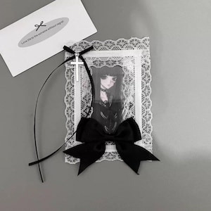 May include: A framed picture with a black bow and a silver cross. The picture has a white lace border and features a gothic anime-style illustration. A card with the text "Love life to the extreme without regret" is also present.