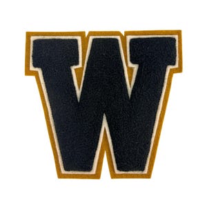 May include: A varsity-style letter W patch featuring a textured black center, a white middle border, and a gold outer border. The letter has a block typeface design with thick, bold lines and a fuzzy, felt-like material finish on the surface.