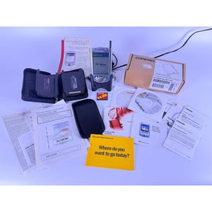 May include: A collection of vintage Compaq iPAQ Pocket PC accessories and documentation. Includes a handheld device, a black case, a 64 MB memory card, software CDs, and various manuals. A yellow card reads "Where do you want to go today?"