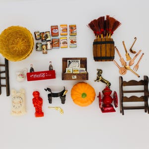 May include: A collection of miniature items including a yellow woven basket, small food cans, a wooden barrel with brooms, copper-colored utensils, a ladder, a Coca-Cola crate, a seed display, a pumpkin, a red coffee mill, and a wooden shelf.