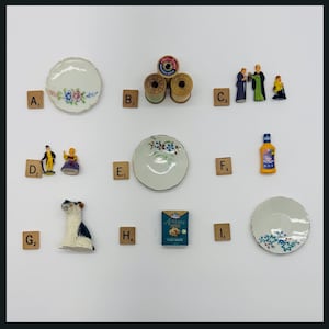 May include: An assortment of miniature objects, including decorative plates with floral designs, spools of thread, figurines, a dog figurine, and a bottle of cleaner. The items are arranged on a white surface.