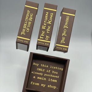 May include: Three brown book-shaped boxes with gold lettering, titled "The Fellowship of the Ring", "The Return of the King", and "The Two Towers" by J.R.R. Tolkien. A brown box with text that reads "Buy this listing ONLY if You already purchased a main item from my shop."