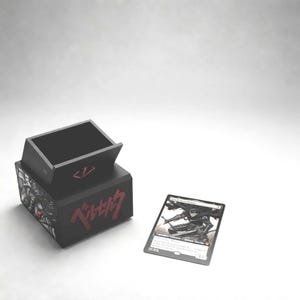Peut inclure: Boîte de rangement de cartes noire avec texte japonais rouge et un motif graphique. Une carte à collectionner avec une illustration en noir et blanc d'un personnage est à côté de la boîte. La boîte a un design unique.