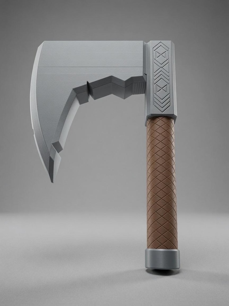 May include: A grey axe with a wide, flat blade featuring a notched underside. The head includes a rectangular section with engraved geometric patterns. The handle is cylindrical with a brown, diamond-textured grip and a solid grey base cap.