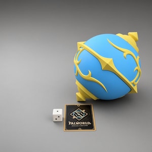 Könnte beinhalten: Ein kugelförmiges blaues Objekt mit gelben Zierleisten, ein weißer sechsseitiger Würfel mit schwarzen Punkten und eine rechteckige Palworld Official Card Game Karte mit einem zentralen Emblem und goldenem Rand auf grauem Grund.
