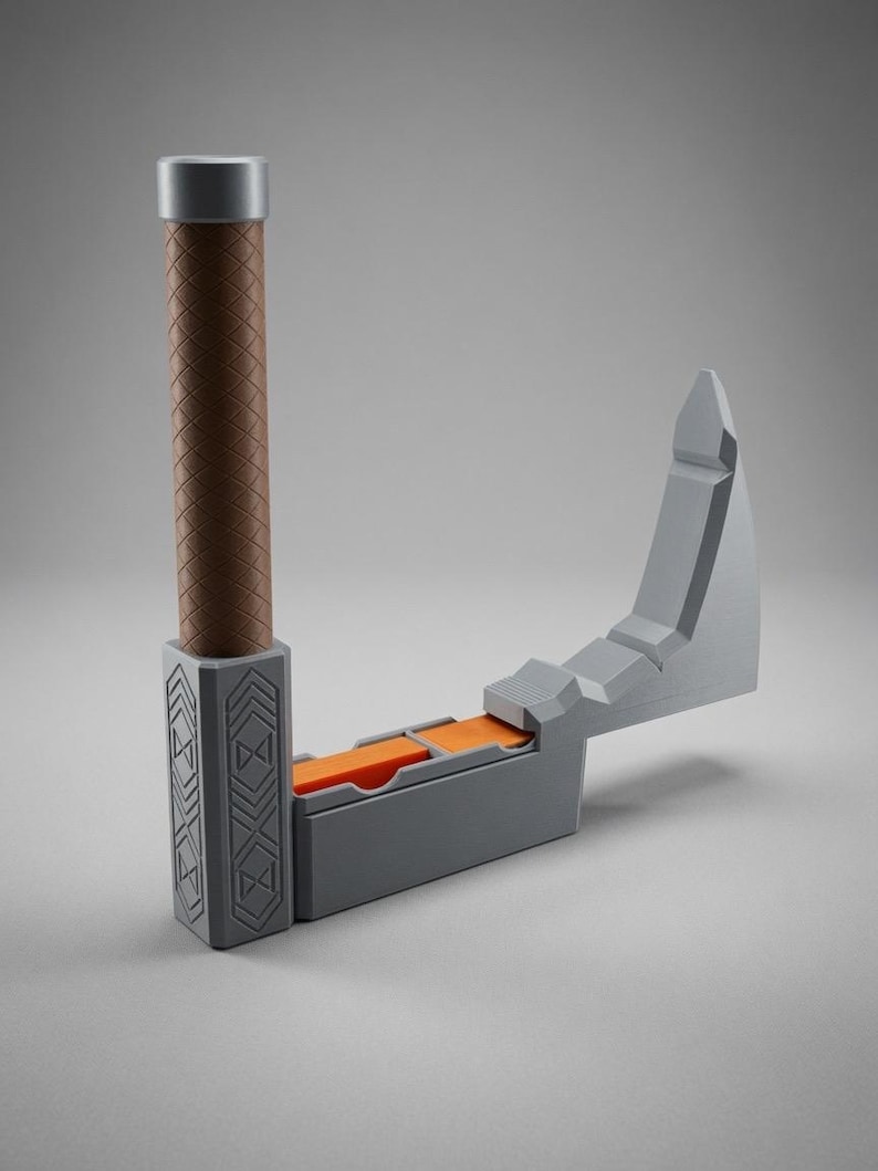 May include: A grey and brown axe-shaped object with a vertical handle featuring a cross-hatched texture. The base is rectangular with geometric engravings, and the horizontal blade section reveals bright orange interior segments.