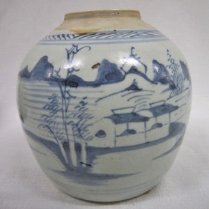 May include: A white ceramic jar with a blue and white landscape design. The jar has a round body and a narrow neck. The landscape design features mountains, trees, and a building.
