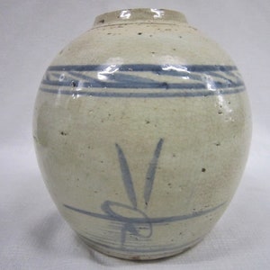 May include: A white ceramic jar with blue and white painted designs. The jar has a round body and a narrow opening. The jar is decorated with a band of blue and white stripes around the top and a blue and white floral design on the front.