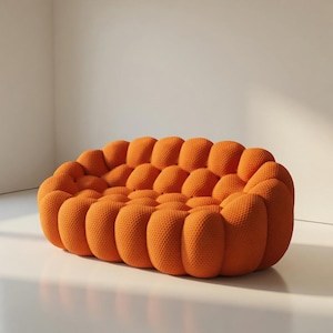 Può includere: Un divano arancione contemporaneo con un design unico e strutturato. Il divano presenta una serie di forme arrotondate a bolla, creando una disposizione di seduta visivamente interessante e confortevole. Il colore è un arancione vivace e caldo, su sfondo bianco.