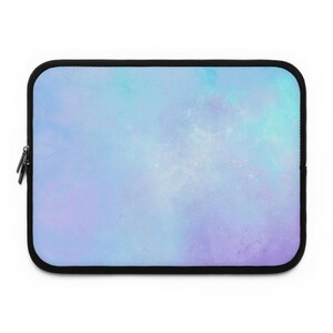 Puede incluir: Una funda rectangular para portátil con un diseño celestial. La funda presenta un degradado de azul claro, morado y blanco, que se asemeja a una nebulosa o galaxia. Tiene un borde negro y un cierre de cremallera.