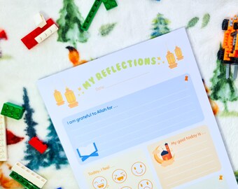 May include: A white paper with the text "MY REFLECTIONS" in light green, with space to write. The page has illustrations of lanterns and a mosque. Colorful building blocks surround the paper.