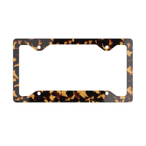 May include: A rectangular license plate frame with a tortoiseshell pattern. The frame has a glossy finish and features a repeating pattern of brown and black spots. The frame has four pre-drilled holes for mounting.