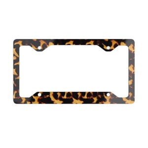 May include: A rectangular license plate frame featuring a classic brown and black tortoiseshell pattern. The frame has four circular mounting holes positioned at the corners, designed to secure a standard vehicle license plate securely in place.