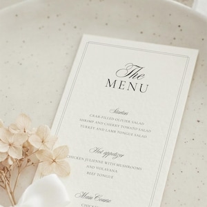 May include: A rectangular off-white menu card with black text featuring the headings The Menu, Starters, Hot appetizer, and Main Course, with a list of food items including crab-filled Olivier salad, shrimp, turkey, lamb tongue, and chicken julienne.