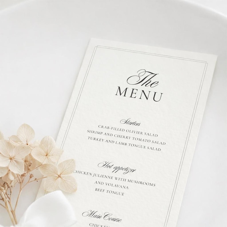 May include: A white rectangular menu card with black text featuring the headings The Menu, Starters, Hot appetizer, and Main Course, accompanied by a cluster of cream-colored hydrangea flowers and a white ribbon positioned at the bottom left corner.