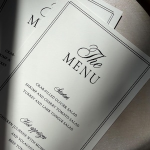May include: A white paper menu with black text and a double-line border. The header reads The MENU, followed by Starters including Crab-filled Olivier salad, Shrimp and cherry tomato salad, and Turkey and lamb tongue salad, plus Hot appetizer.