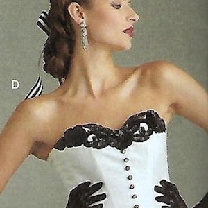 May include: A white strapless corset with black lace detailing and a row of buttons down the front. The model is wearing black lace gloves and earrings. The overall theme is formal wear.