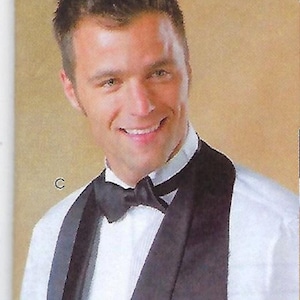 May include: A white dress shirt paired with a black bow tie and a black vest featuring a wide lapel. The shirt has a classic collar and the vest is worn over the shirt. The letter C is printed in white on the left side of the image.