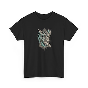 Może przedstawiać: Czarny t-shirt z krótkim rękawem z centralną grafiką przedstawiającą królika z długimi uszami, otoczonego wirującym niebieskim dymem, umieszczonego w ozdobnej, ciemnej prostokątnej ramie z symbolem półksiężyca u góry.