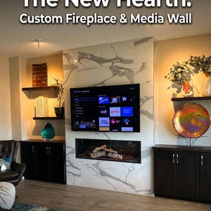May include: A modern living room with a custom fireplace and media wall. The fireplace has a marble-like surround and a built-in electric fire. A large TV is mounted above the fireplace. The text reads: "The New Hearth: Custom Fireplace & Media Wall."