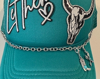 Blågrön truckerkeps med tjurskalle och stövelberlocker