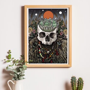 May include: A framed illustration of a skull with a detailed drawing of Stonehenge inside the skull. The skull is adorned with a variety of beads, feathers, and other decorative elements. The background is a dark green with a red sun and white stars.