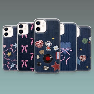 Può includere: Cinque custodie per smartphone con texture denim e varie toppe decorative. I disegni includono Snoopy, cuori, stelle, fiocchi e la scritta "ALL YOU NEED IS LOVE". Le custodie hanno un bordo trasparente.