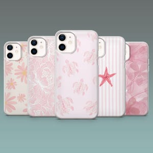 Può includere: Una collezione di cinque custodie per telefoni con vari design. Le custodie presentano motivi floreali, di tartarughe e di stelle marine nei toni del rosa e del bianco. Le custodie sono esposte su uno sfondo turchese.