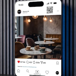 Puede incluir: Una pantalla de smartphone muestra el interior de una cafetería con mesas redondas de mármol, sillas de terciopelo y lámparas colgantes. La publicación de Instagram muestra tazas de café, un logotipo y el texto "deqora.de #socialmirror #madeingermany".