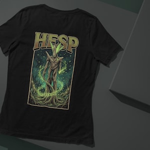 Pode incluir: Uma caneca de cerâmica branca com uma alça preta e o texto "But First, Coffee" em negrito preto. A caneca está sobre um fundo desfocado, sugerindo um ambiente acolhedor.