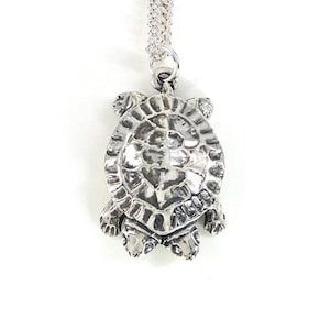 May include: A silver turtle pendant necklace. The turtle is detailed with a textured shell and is hanging from a silver chain.