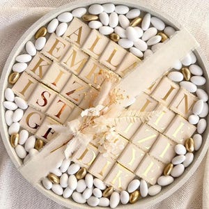 Könnte beinhalten: Ein Set aus drei Keramikbechern mit gesprenkelter, matter Oberfläche. Die Becher sind in Creme-, Hellgrau- und Dunkelgrautönen gehalten. Jeder Becher hat ein schlichtes, minimalistisches Design.