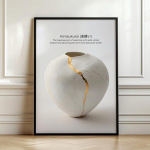 May include: A framed wall art print featuring a white ceramic vase with a gold-filled crack, illustrating the Kintsukuroi technique. The text reads: Kintsukuroi (金繕い) The Japanese art of repairing with gold, where brokenness becomes part of a more beautiful whole.