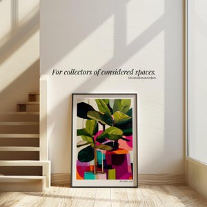 May include: A framed art print featuring a stylized fiddle leaf fig plant with large green leaves, set against a vibrant, abstract background of pink, orange, and teal geometric shapes. The text "PICASSO 1927" is printed at the bottom of the print.