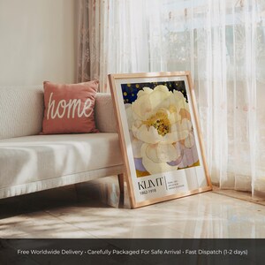 May include: A framed art print featuring a large, pale yellow and white flower with gold-toned accents against a dark blue background. The bottom of the print displays the text KLIMT, 1862-1918, and additional small text in a clean, modern font.