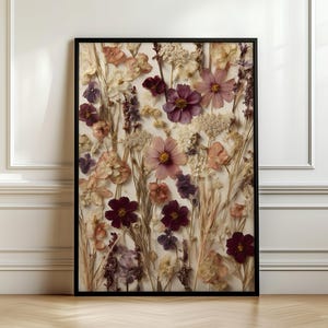 May include: A rectangular wall art piece featuring a collection of pressed dried flowers in shades of deep purple, soft pink, cream, and beige. The botanical arrangement is encased in a thin black frame, displaying various petals, stems, and grasses.