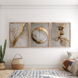 Op de afbeelding: Een set van drie rechthoekige wandkunstprints in lichte houten lijsten. De linkerprint toont een gouden boomtak, de middelste print bevat een gouden cirkelvormige abstracte vorm en de rechterprint toont een menselijk gezichtsprofiel met goud.