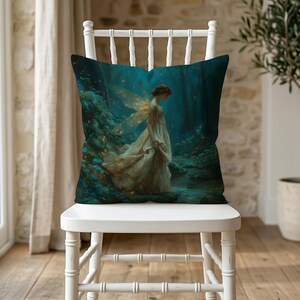 Op de afbeelding: Een vierkant sierkussen met een bedrukte illustratie van een figuur met doorschijnende vleugels in een vloeiende crèmekleurige jurk, staand in een donker, betoverd bos met gloeiende blauwe accenten en gouden lichtdeeltjes.