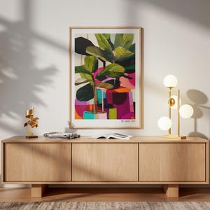 May include: A framed art print featuring a stylized potted plant with large green leaves against a vibrant background of pink, purple, and orange geometric shapes, with the text PICASSO 1927 printed in the bottom right corner of the white border.