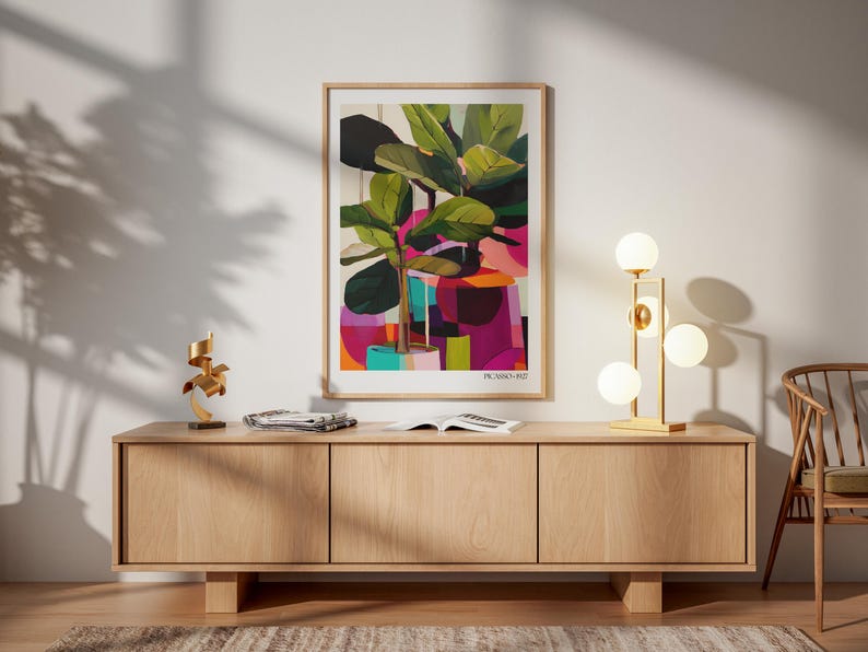 May include: A framed art print featuring a stylized potted plant with large green leaves against a vibrant background of pink, purple, and orange geometric shapes, with the text PICASSO 1927 printed in the bottom right corner of the white border.