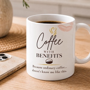 May include: A white ceramic mug featuring a brown graphic design with the text Coffee WITH BENEFITS and a coffee bean icon. A light pink lipstick kiss mark is printed near the rim. The text below reads Because ordinary coffee... doesn't know me like this.