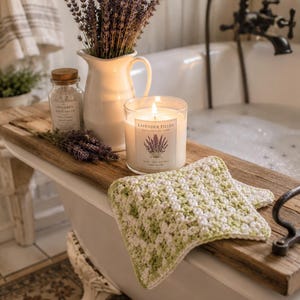 May include: A white ceramic pitcher filled with dried lavender, a glass candle labelled Lavender Fields, and a small glass jar of bath salts sit on a wooden tray. A square, light green and white crocheted washcloth rests on the tray surface.