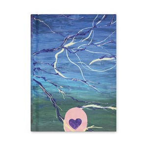 May include: A rectangular hardcover journal with an abstract design. The cover has a blue and green background with white and purple branch-like lines. A pink circle with a purple heart is in the lower centre.