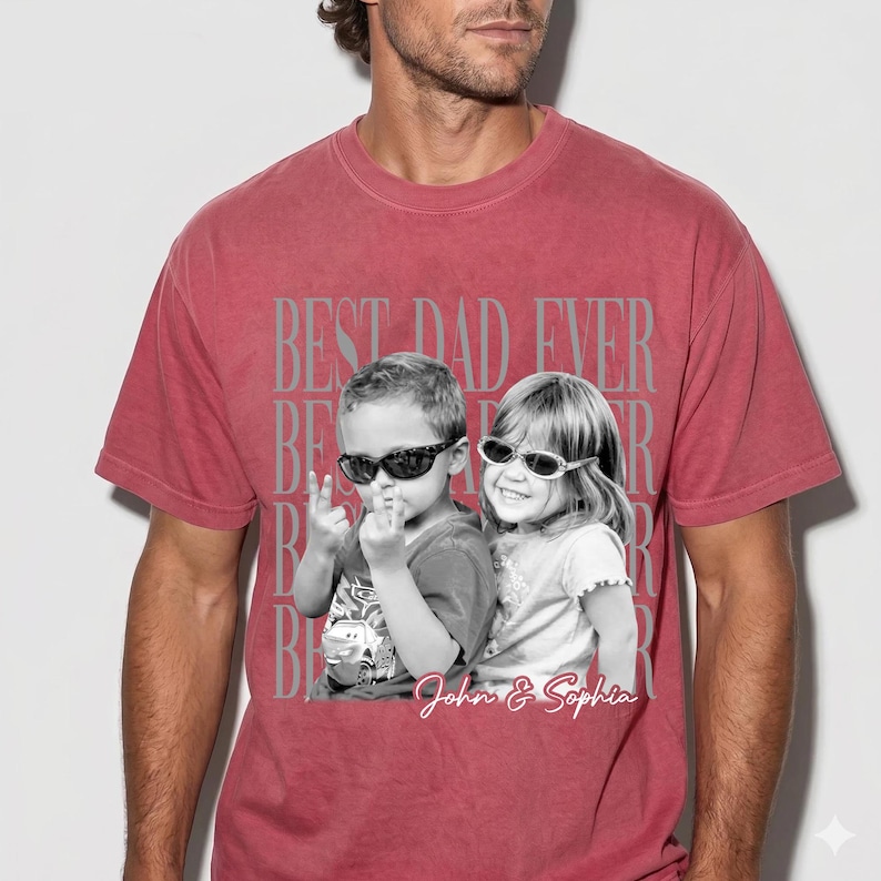May include: Red t-shirt with the text "BEST DAD EVER" in gray, with a black and white image of two children wearing sunglasses. The children's names, "John & Sophia," are written in cursive below the image.