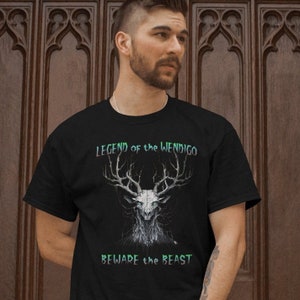 Pode incluir: Camiseta preta com um gráfico branco de um crânio de veado com chifres. O texto "LEGEND of the WENDIGO" está acima do crânio e "BEWARE the BEAST" está abaixo.